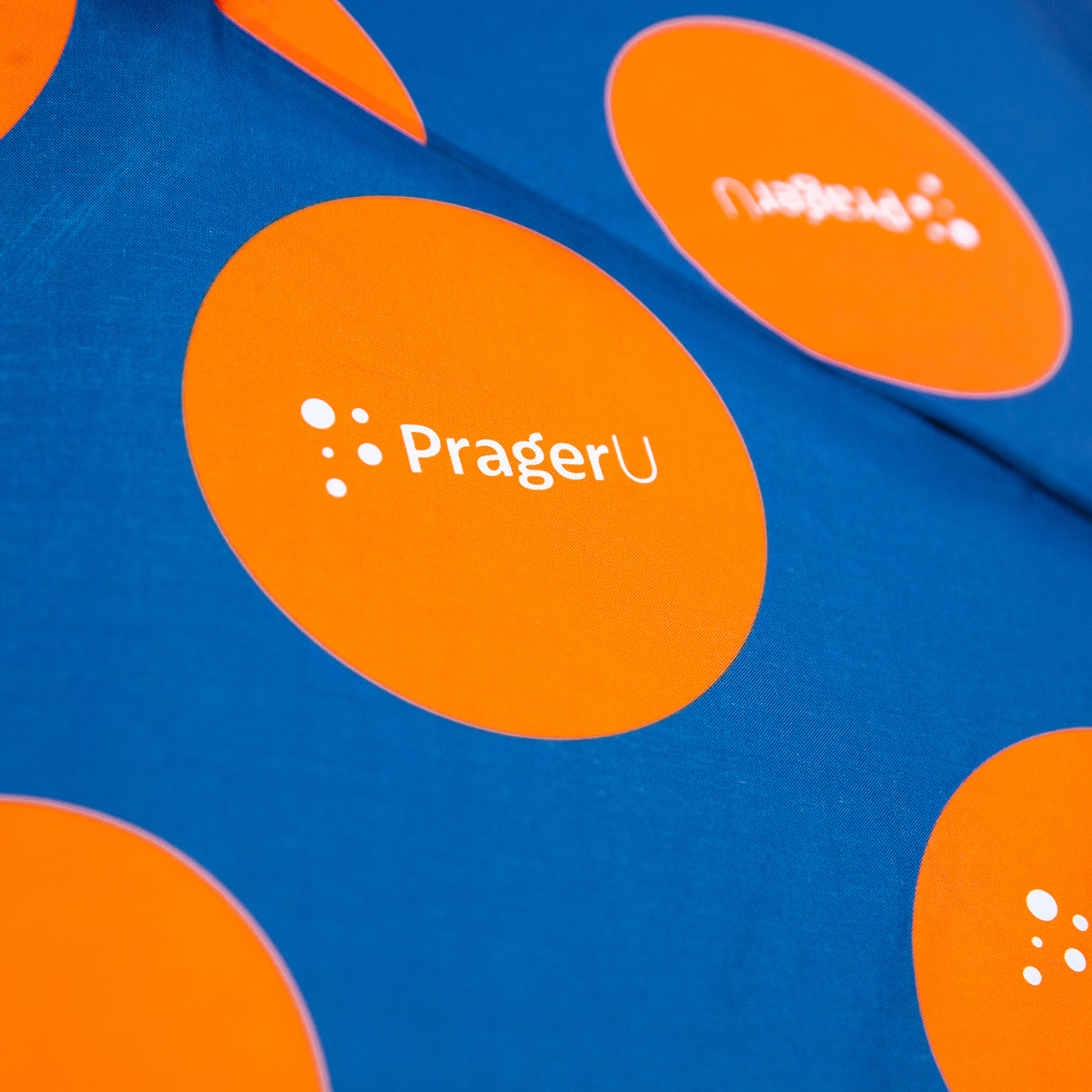 PragerU logo umbrella open, showing black canopy with white PragerU logo, designed for rain protection and style.