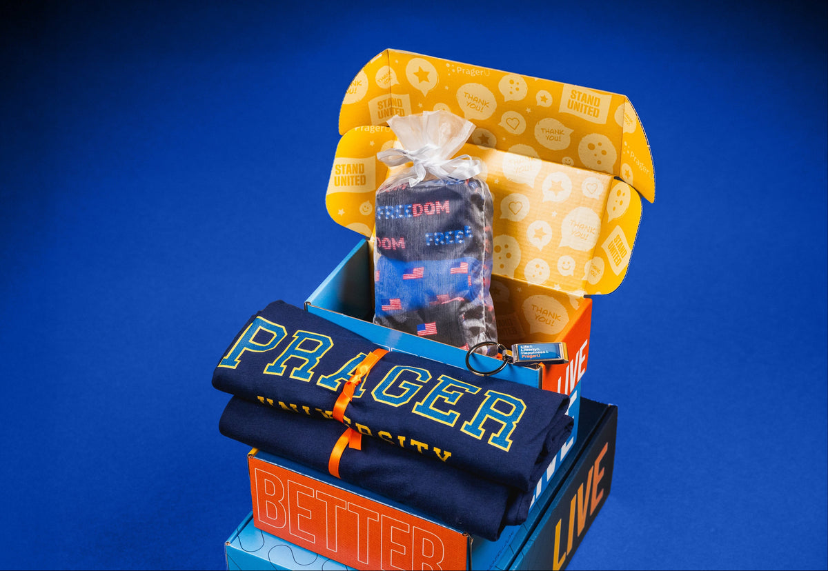 Open PragerUnited membership box with a folded PRAGER UNIVERSITY shirt and Freedom socks on a blue background