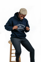Beige PragerU "Stand for Freedom" hoodie featuring the logo, displayed on a hanger against a plain background.