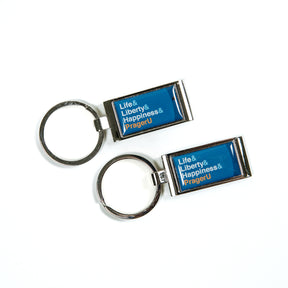 PragerU keychain with logo and branding, made of metal, featuring the PragerU name and design on the surface.